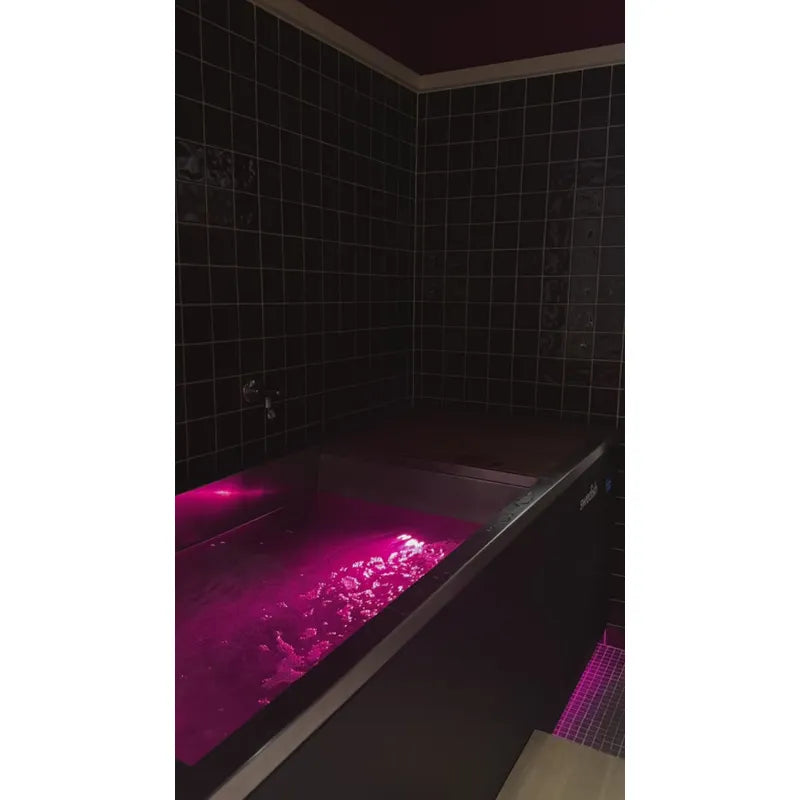 Swedish Cold Generation 4S Eisbad 190x78x87 mit leuchtend pinkem Wasser in modernem Badezimmer mit schwarzen Fliesen