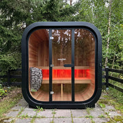 Swedish Cold Grand Escape Gartensauna 4 Personen 90°C mit schwarzem Außenrahmen, Holzinnenraum und roter Infrarotheizung im Garten