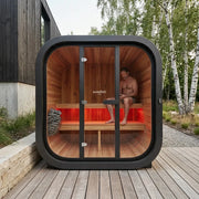 Swedish Cold Grand Escape Gartensauna 4 Personen 90°C mit schwarzem Rahmen, Holzinnenraum und roten Leuchten im modernen Garten