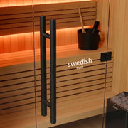 Swedish Cold Heritage traditionelle Sauna mit Holzbänken, schwarzen Glastürgriffen und orangener Beleuchtung im Innenraum