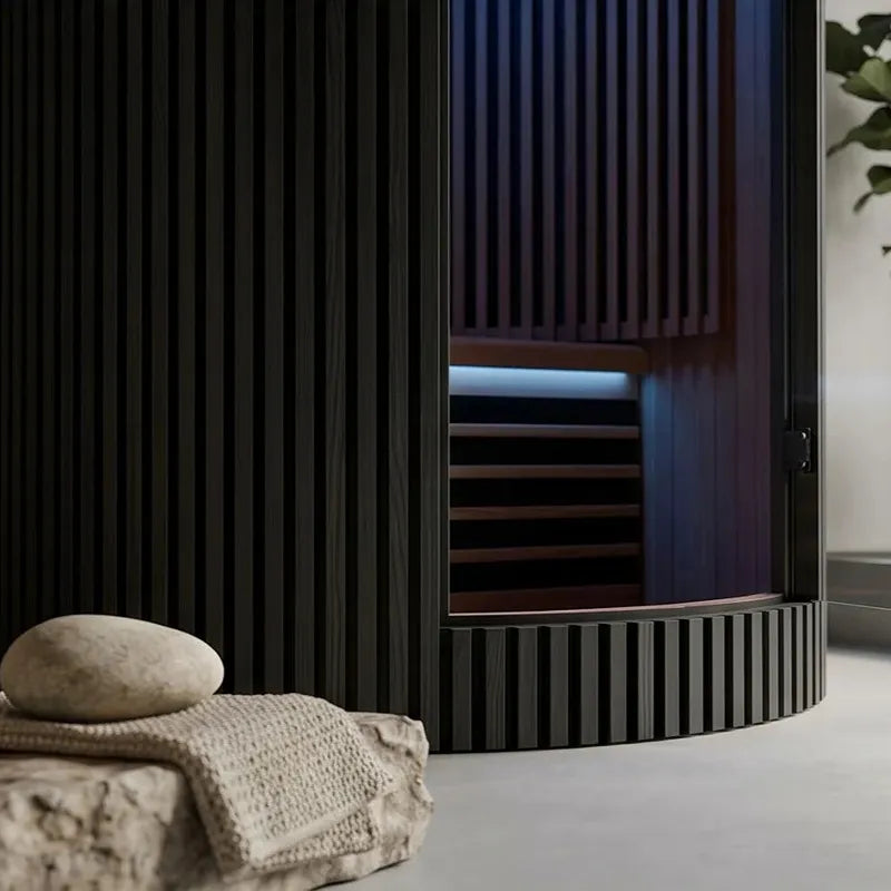 Swedish Cold Sanctuary Solo Infrarot-Innensauna 1 Person mit schwarzem Gehäuse und Holzblick innen, daneben Handtuch und Wellness-Accessoires