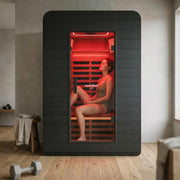 Swedish Cold Ultimate Lux Infrarot-Innensauna Rotlicht 1-2P mit Frau in Innenraum, schwarze Außenverkleidung, rote Rotlichttechnologie