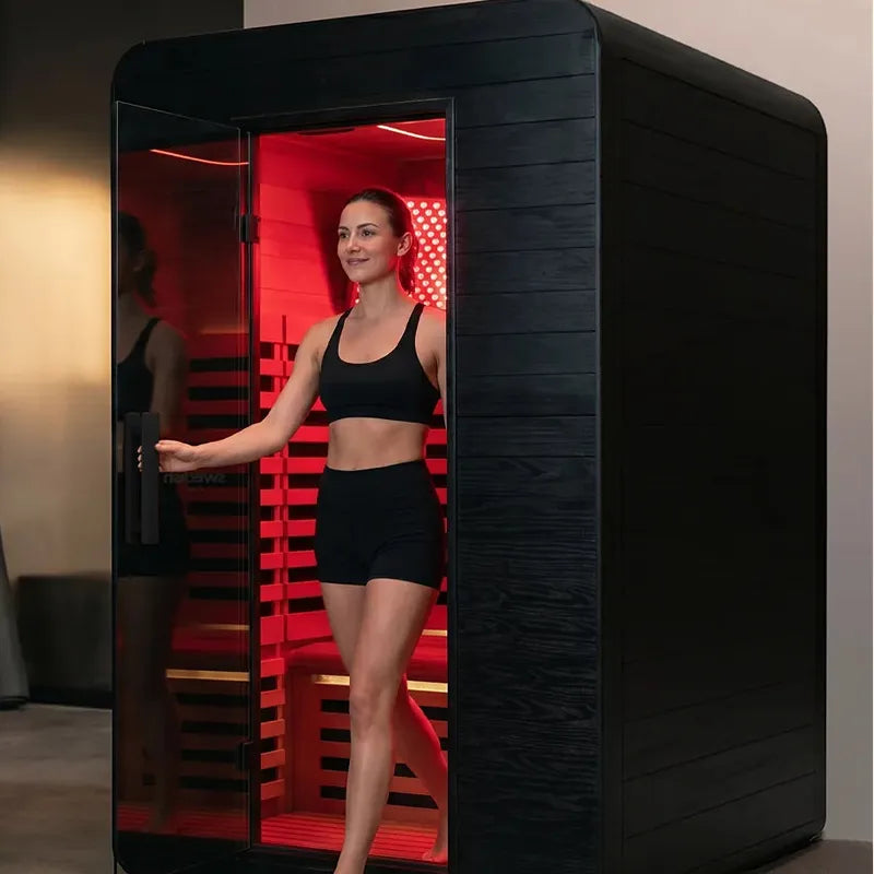 Frau in Swedish Cold Ultimate Lux Infrarot-Innensauna Rotlicht 1-2P mit rotem Infrarotlicht und schwarzem Gehäuse