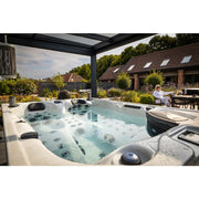 Outdoor-Installation des Topaz Whirlpools mit zwei Loungesitzen in stilvoller Gartengestaltung – luxuriöse Wellnessatmosphäre im eigenen Zuhause