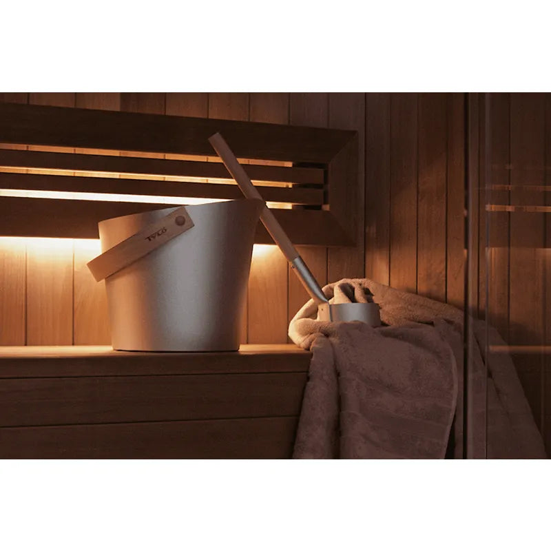 Tylö Brilliant Sauna-Set Eimer & Kelle Silber in moderner Sauna mit Holzbänken und Handtuch