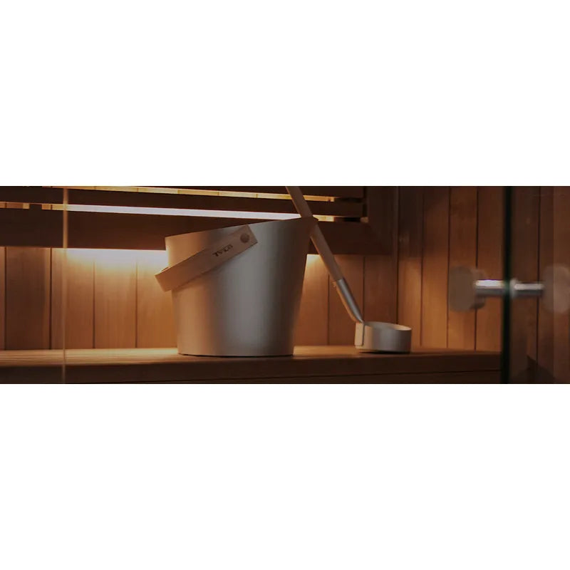 Tylö Sense Sport Compact Saunaofen mit Steinen und Kelle in holzvertäfelter Sauna mit warmer Beleuchtung