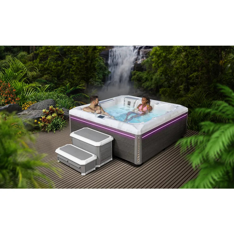 Wellis Atlas Life Premium Whirlpool mit 6 Sitzen und 43 Jets im Garten mit Wasserfallkulisse