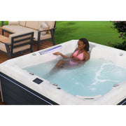 Wellis Atlas Life Premium Whirlpool mit Frau in türkisem Wasser, weiße Wanne, Garten im Hintergrund