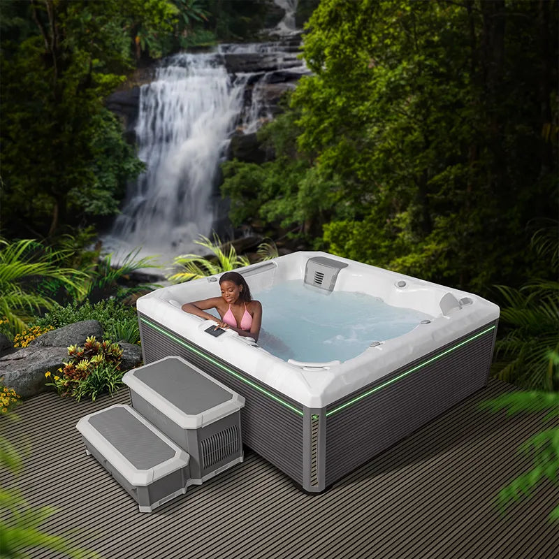 Wellis Atlas Life Whirlpool mit 6 Sitzen in grüner Gartenumgebung an Wasserfall