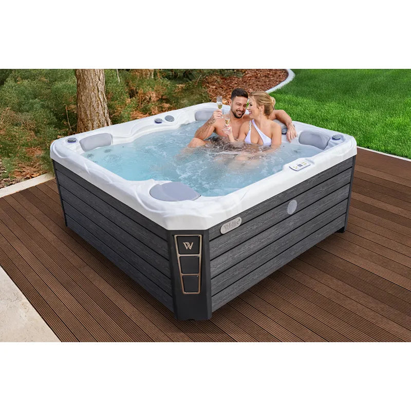 Wellis Budapest Life Premium-Whirlpool mit zwei Personen im warmen Wasser auf Holzterrasse im Garten