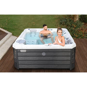 Wellis Budapest Life Premium-Whirlpool mit zwei Personen in türkisblauem Wasser auf Holzterrasse im Garten