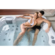Wellis Budapest Life Whirlpool mit zwei Personen in blauem Wasser, Massagedüsen sichtbar, moderne Terrasse