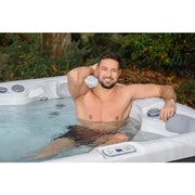 Mann entspannt in Wellis Budapest Life Premium-Whirlpool mit Wasserjets und Steuerungspanel im Garten
