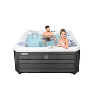 Wellis Budapest Life Premium-Whirlpool mit zwei Personen in türkisblauem Wasser, weißer Wanne und dunkelgrauer Holzoptik-Umrandung