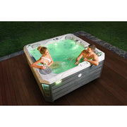 Wellis Budapest Life Premium-Whirlpool mit zwei Personen im grün beleuchteten Wasser auf Holzterrasse