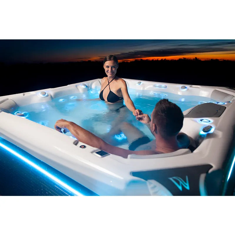Wellis Elbrus Life Premium Whirlpool mit zwei Personen bei Sonnenuntergang, bleuchtete Jets und moderne Designelemente