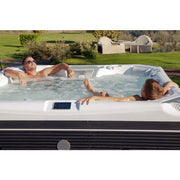 Wellis Elbrus Life Premium Whirlpool mit zwei Personen im warmen Wasser, Garten im Hintergrund