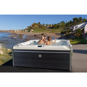 Wellis Elbrus Life Premium Whirlpool mit 7 Sitzen in Strandlage, zwei Personen entspannen im warmen Wasser