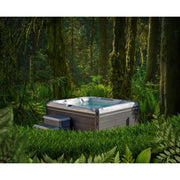 Wellis Everest Life Premium Whirlpool mit 5 Sitzen und 68 Jets im Wald positioniert, umgeben von Moos, Farnen und alten Bäumen