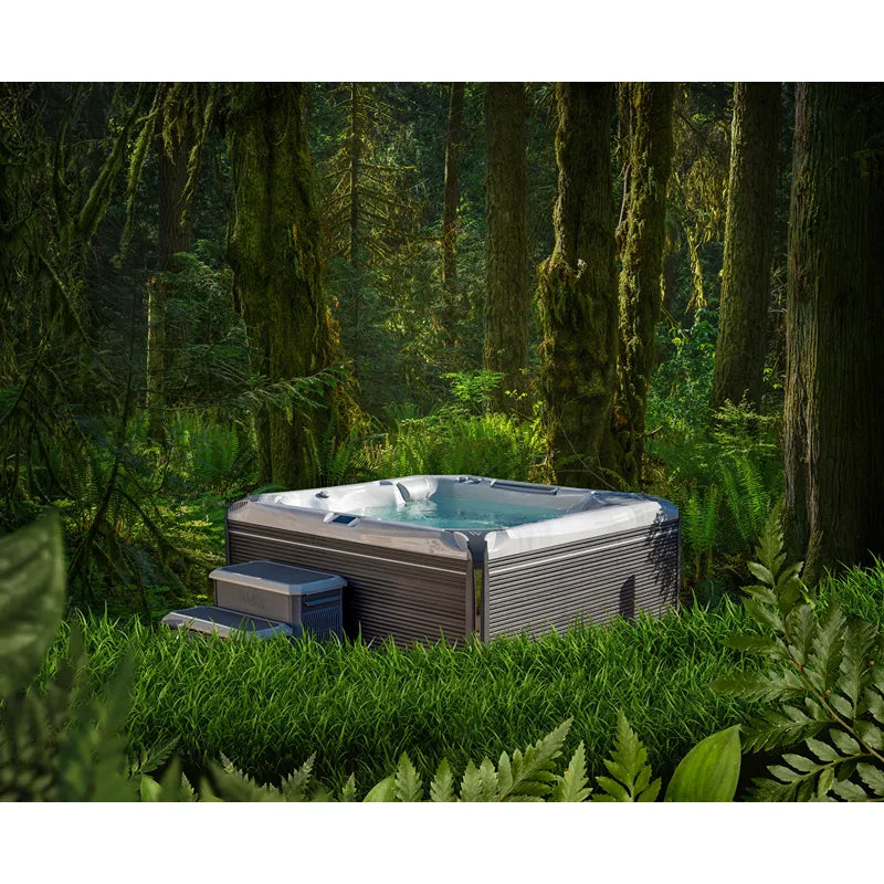 Wellis Everest Life Premium Whirlpool mit 5 Sitzen und 68 Jets im Wald positioniert, umgeben von Moos, Farnen und alten Bäumen