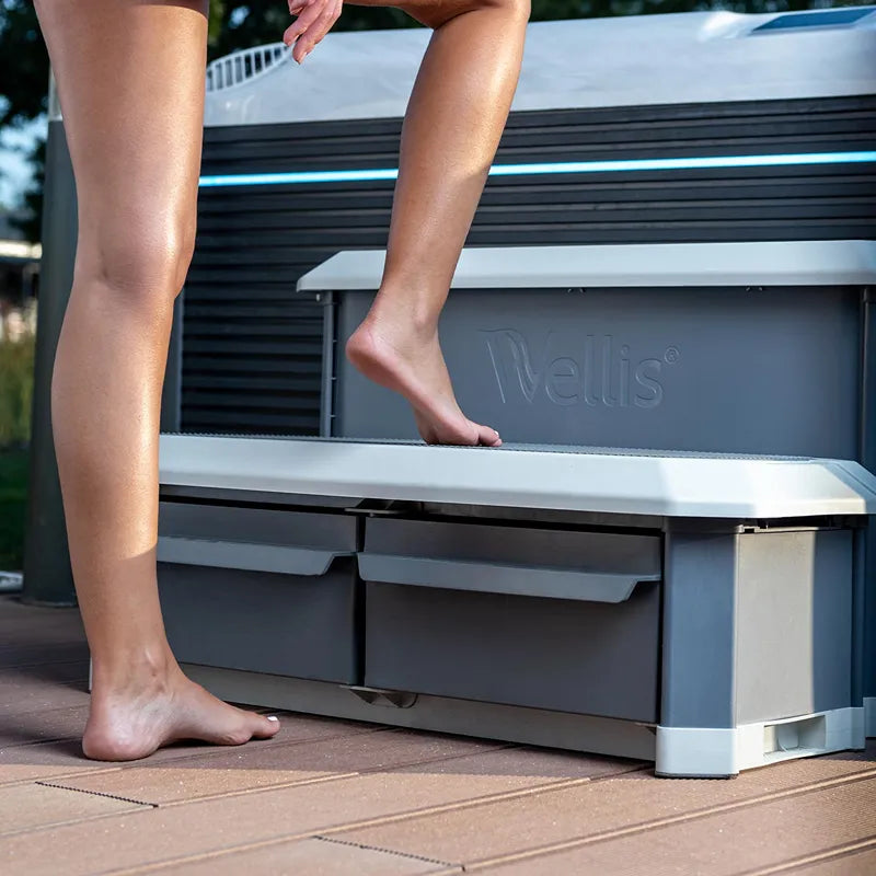Wellis Everest Life Premium Whirlpool mit Person beim Einstieg, modernes Design mit weißer Umrandung und schwarzen Seitenpanelen im Garten