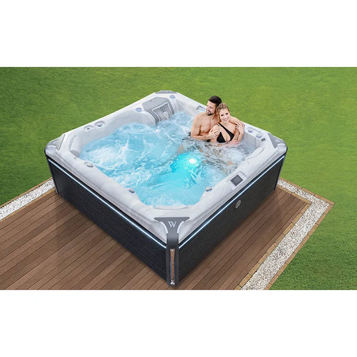 Wellis Kilimanjaro Life Premium Whirlpool mit 6 Sitzplätzen und 59 Jets im Garten, zwei Personen entspannen im sprudelnden Wasser