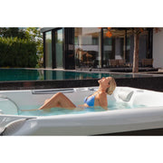 Wellis Kilimanjaro Life Premium Whirlpool mit Frau in Garten, Wasserstrahlen und Nackenauflage sichtbar
