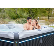 Wellis Kilimanjaro Life Premium Whirlpool mit Paar entspannend im warmen Wasser, moderne weiße Beckenkonstruktion mit blauen LED-Leuchten