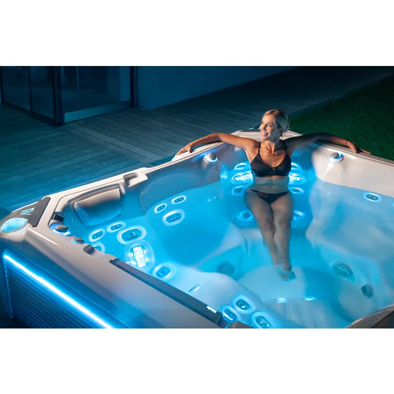 Wellis Kilimanjaro Life Premium Whirlpool mit 6 Sitzen und 59 Jets, Frau entspannt im beleuchteten Whirlpool auf der Terrasse