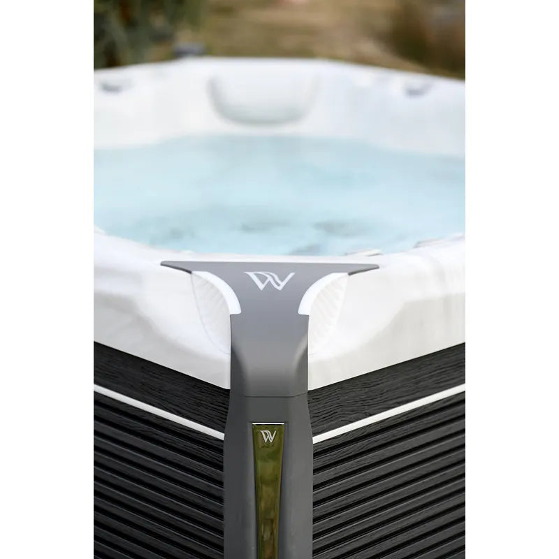 Wellis Kilimanjaro Life Premium Whirlpool mit weißem Rand, grauem Kopfstützen-Detail und schwarzem Holzverkleidung in Gartenumgebung