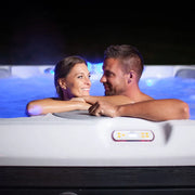 Paar entspannt sich im Wellis Lima Life Premium-Whirlpool mit blauer LED-Beleuchtung und Bedienfeld