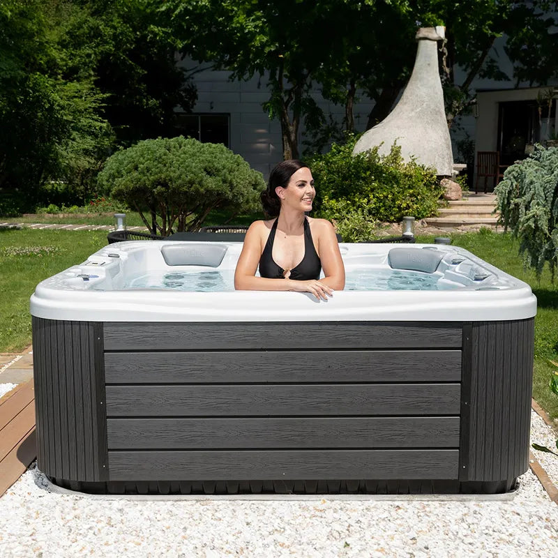 Wellis Lugano Life Premium-Whirlpool mit Frau in Garten, grauer Holzverkleidung und weißem Rand