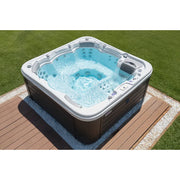 Wellis Lugano Life Premium-Whirlpool mit sprudelndem Wasser, weißer Rand und dunkelgrauer Außenseite auf Holzterrasse