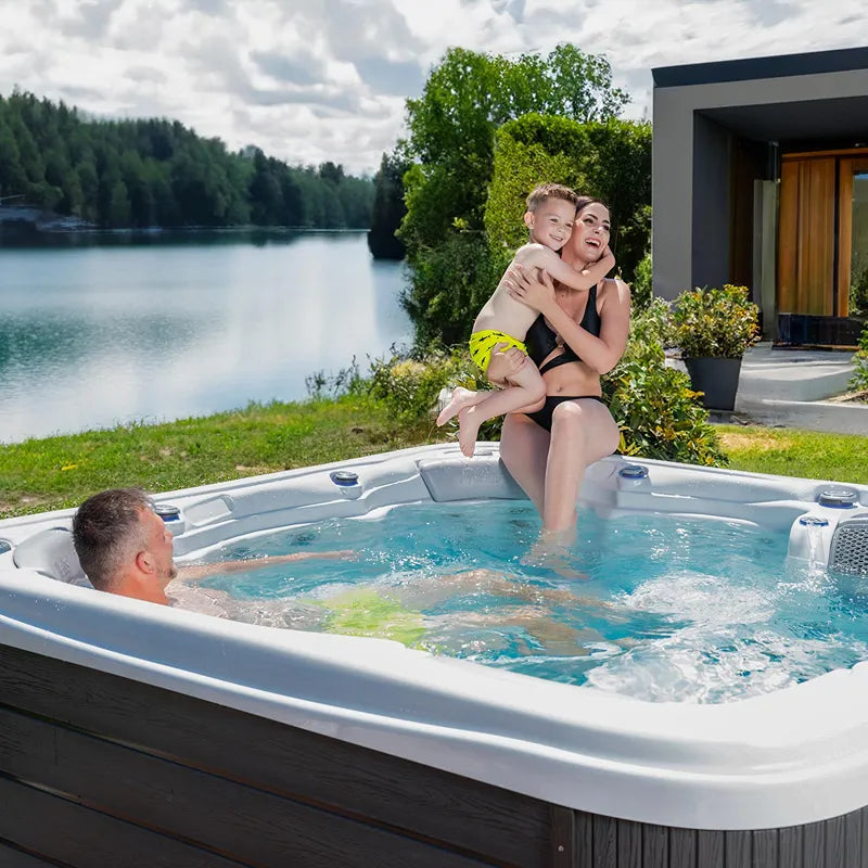 Wellis Lugano Life Premium-Whirlpool mit Familie am See, Mutter und Kind am Beckenrand, Vater im Wasser