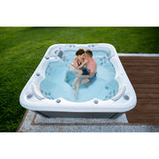 Wellis Lugano Life Premium-Whirlpool mit zwei Personen im warmen Wasser, im Garten auf Holzterrasse