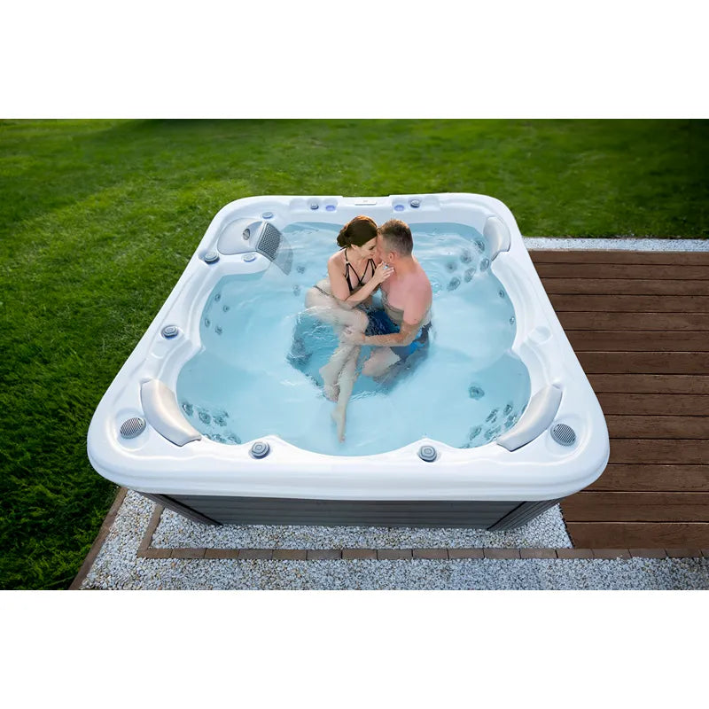 Wellis Lugano Life Premium-Whirlpool mit zwei Personen im warmen Wasser, im Garten auf Holzterrasse