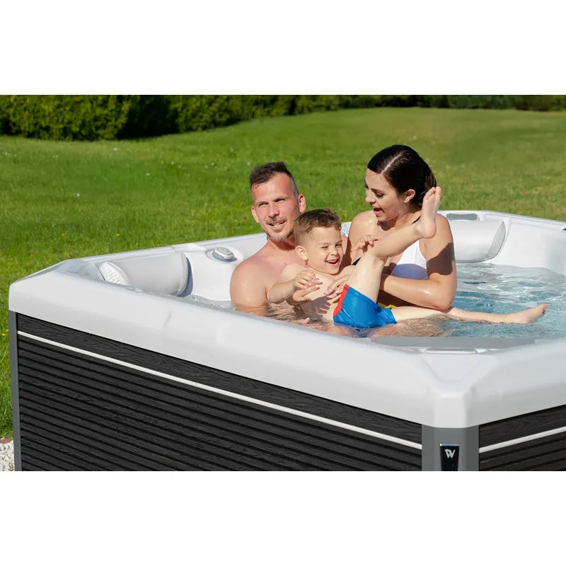 Wellis Makalu Life Premium Whirlpool mit Familie im Garten, 5 Sitze, sprudelndes Wasser, weißes Becken mit schwarzem Rahmen