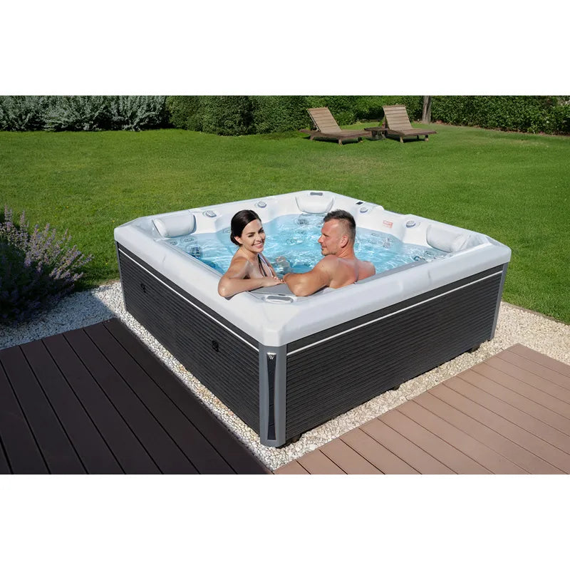 Wellis Makalu Life Premium Whirlpool mit 5 Sitzen und 51 Jets im Garten, zwei Personen entspannen im sprudelnden Wasser