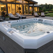 Wellis Malaga Life Premium-Whirlpool mit sprudelndem Wasser auf moderner Terrasse, umgeben von Loungemöbeln und beleuchteter Villa