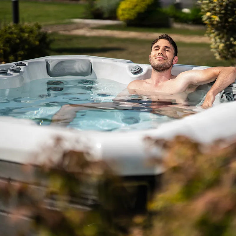 Mann entspannt in Wellis Malaga Life Whirlpool mit sprudelndem Wasser im Garten
