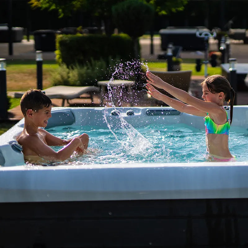 Wellis Malaga Life Whirlpool mit zwei Kindern beim Spielen im Garten, spritzendes Wasser
