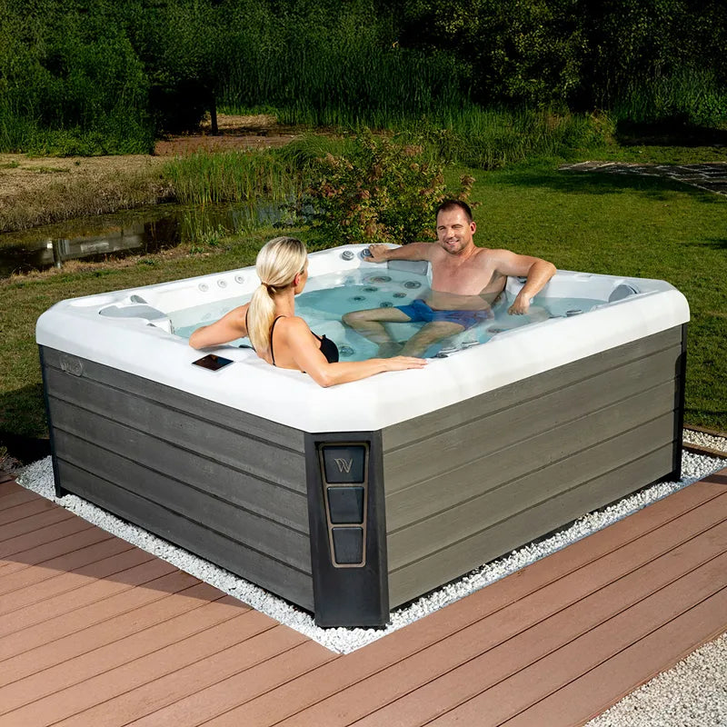 Wellis Malaga Life Premium-Whirlpool mit zwei Personen im Garten, grauer Holzverkleidung und weißem Rand
