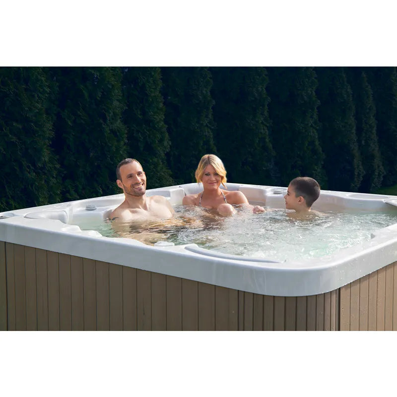 Wellis Malaga Life Premium-Whirlpool mit Familie beim Entspannen im Garten vor Hecke