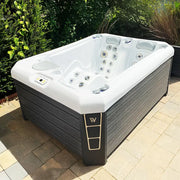 Wellis Manhattan Life Premium-Whirlpool mit weißem Becken und schwarzem Holzgehäuse im Garten