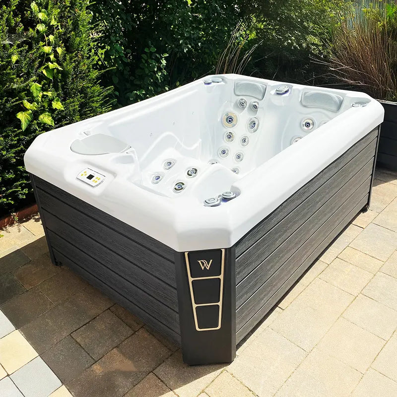 Wellis Manhattan Life Premium-Whirlpool mit weißem Becken und schwarzem Holzgehäuse im Garten