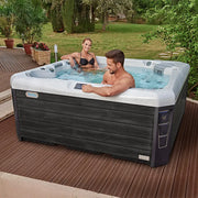 Wellis Palermo Life Premium-Whirlpool mit zwei Personen in Gartensetting auf Holzterrasse