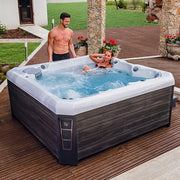 Wellis Palermo Life Premium-Whirlpool mit zwei Personen in entspannter Nutzung auf Holzterrasse im Garten