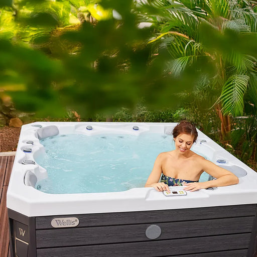 Wellis Prague Life Whirlpool mit Frau in Garten, Palmenhintergrund, weiße Wanne, dunkles Holzdekor
