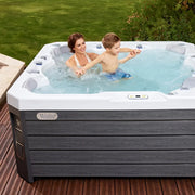 Wellis Prague Life Whirlpool mit Frau und Kind im warmen Wasser auf Terrasse mit Garten
