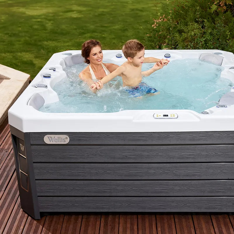 Wellis Prague Life hot tub with woman and child in warm water on terrace with garden